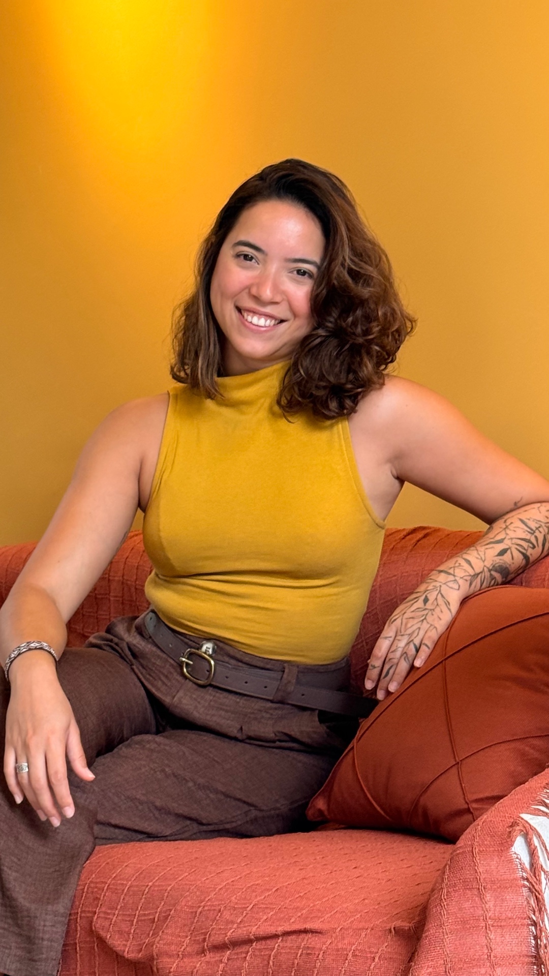 Psicóloga sorrindo, sentada em um sofá acolhedor